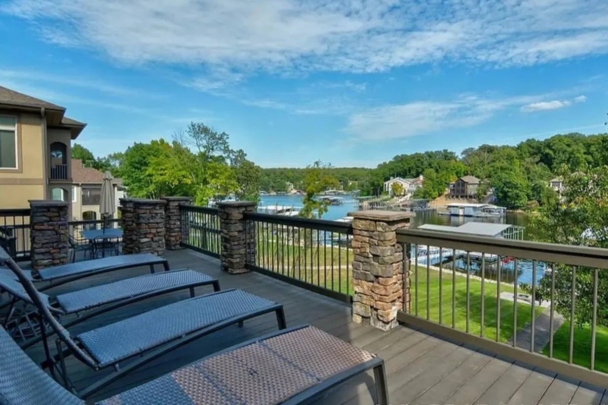 A peaceful lakeside setting featuring lounge chairs overlooking the water, docks stretching out into the lake, and lush greenery surrounding the area. The mood is tranquil, ideal for sunbathing, reading, or launching a day on the water.