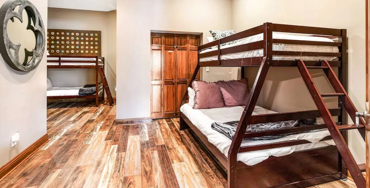 A welcoming laundry room with twin sets of bunk beds, built-in closet, and wooden flooring. The space is bright and practical, offering convenience for large families or groups managing logistics during their stay.