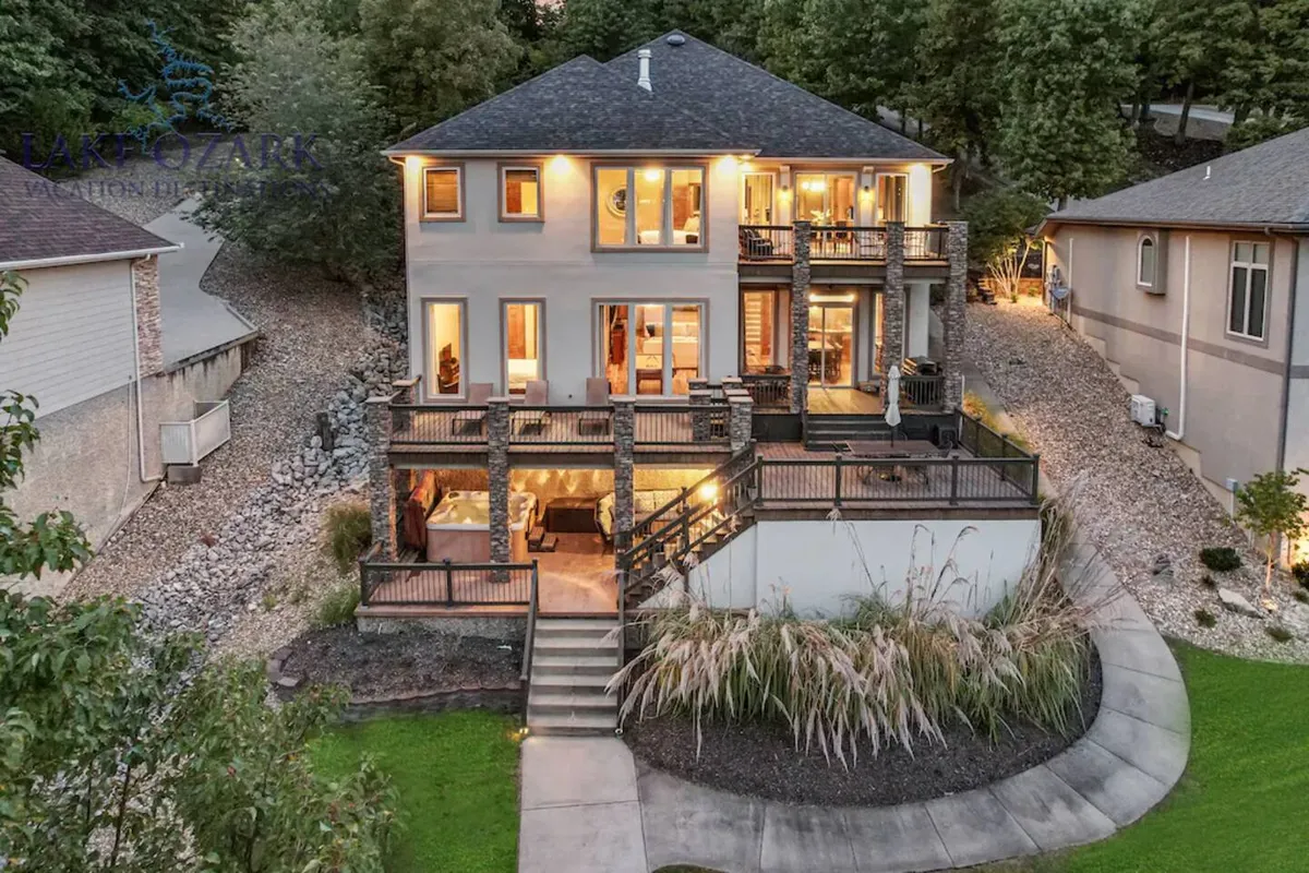 This image highlights a multi-level deck overlooking the lake, showcasing outdoor seating and a landscaped garden. The expansive deck is visible, emphasizing space for gatherings, dining, and relaxing while enjoying gorgeous water views.