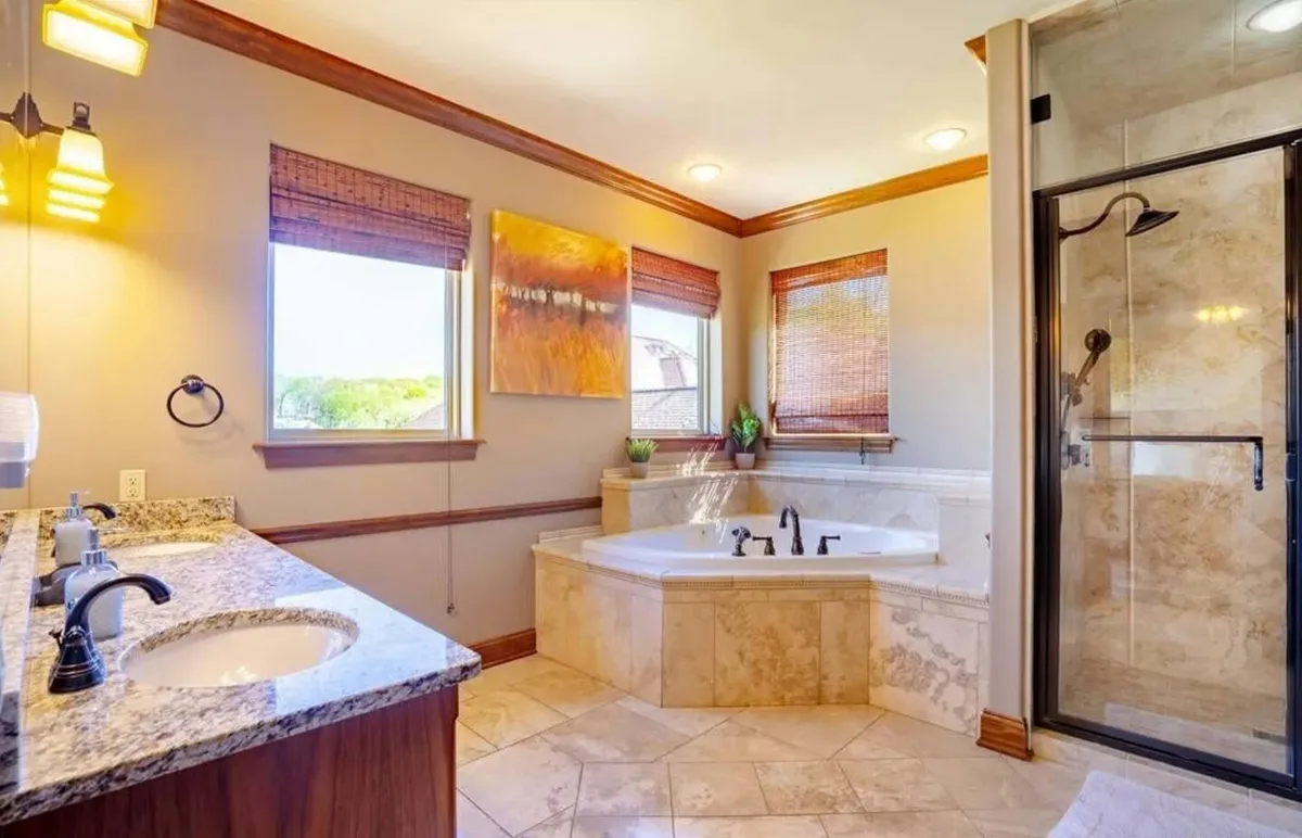 A spa-inspired bathroom with a Jacuzzi tub, double sink vanity, shower enclosure, and elegant wall art. The space is designed for relaxation and offers the feel of a private spa retreat.